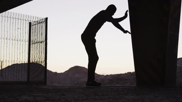 Silhouette of focused african american man exercising outdoors, stretching alt