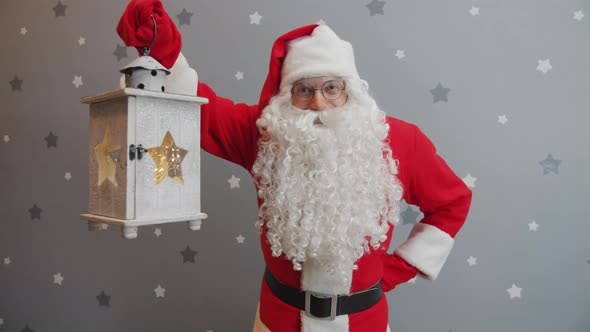 Portrait of Man in Santa Suit Holding Lantern and Smiling Looking at Camera alt