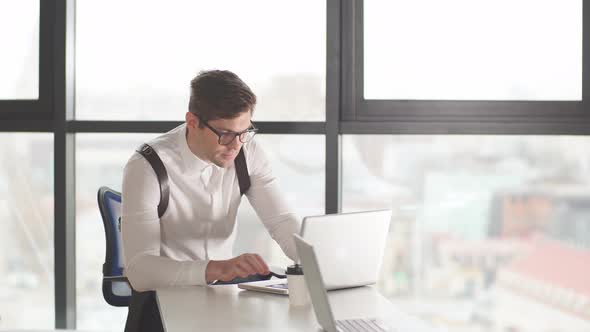 Young Male Financier Sitting at Office Reading Documents with Concentrated Attentive Expression alt