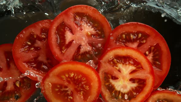 Super Slow Motion Shot of Tomato Slices Falling Into Water on Black Background at 1000Fps. alt