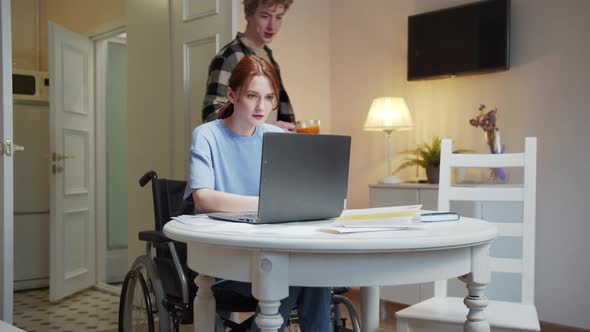 An Attractive Man is Giving His Friend a Cup of Juice During Her Work