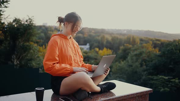 The student with glasses and orange blouse, sitting in the park alt
