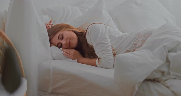 Pretty Young Woman Sleeping in a Bed on a White Pillow