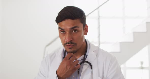 Portrait of happy hispanic male doctor having interview with patient at home alt