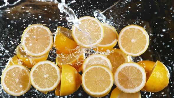 Super Slow Motion Shot of Flying Fresh Lemons and Water Side Splash Isolated on Black at 1000 Fps alt
