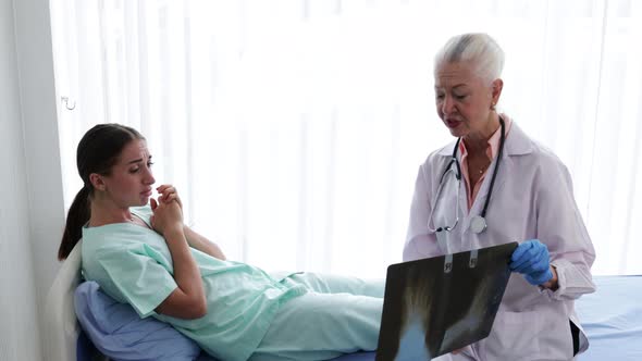 Senior Female doctor explaining the woman patient's results from sick symptoms by X-ray film