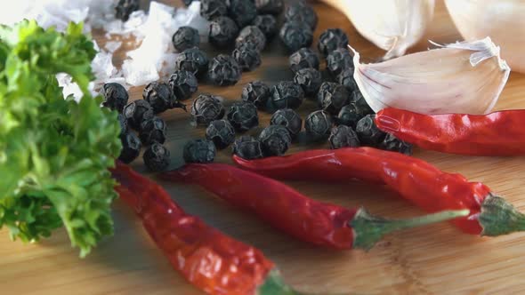 Pepper Salt Chilli and Parsley Ingredients Rotating on a Bamboo Board alt