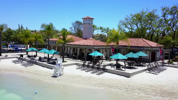 Aerial pan of front of a lake clubhouse at a community sand lagoon pool alt