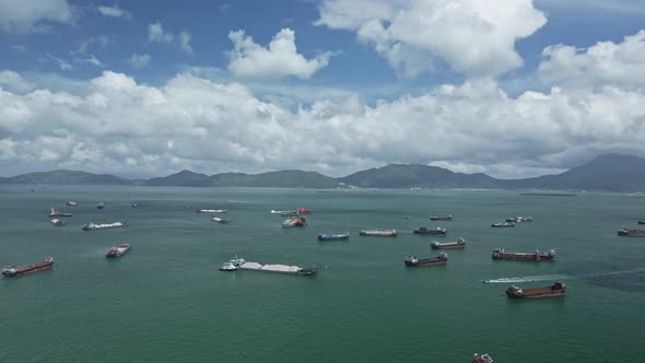 A pan shot of a sea in Tuen Mun where cargo and sand boat idling in the sea. Hong Kong. alt