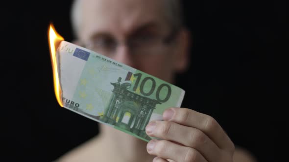 Man Burning One Hundred Euro Banknote on Black Background