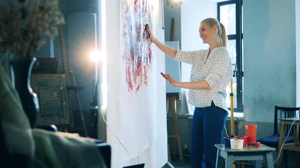 Art Studio with a Blond Lady Painting with Her Hands and Smiling alt
