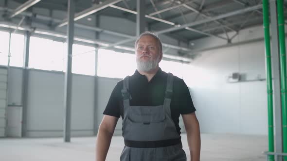 Portrait of Grayhaired Man Worker Walks Through the Warehouse a Working Engineer Walks Through the alt
