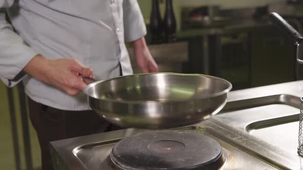 Close Up Shot of the Chef's Hands the Man Warms Up the Olive Oil in a Frying Pan alt