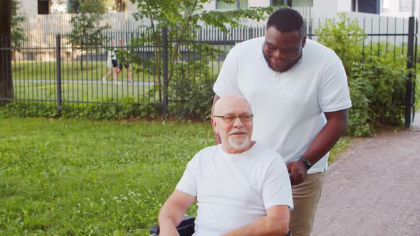 African-American caregiver and old disabled man in a wheelchair. Nurse and patient. alt