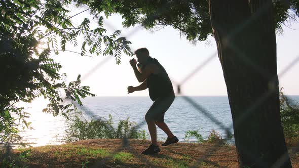 Middle Aged Man with Long Gray Beard Boxing with Shadow in Park During Sunrise Slow Motion alt