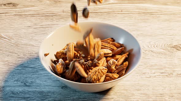 Falling down pecan nuts is filling up the ceramic bowl. Tasty crunchy nuts.Snack alt
