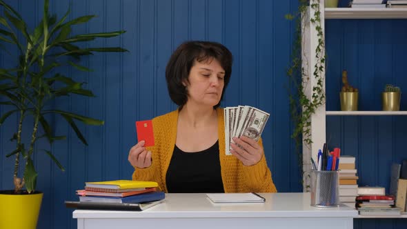 Middle Aged Woman is Holding Credit Card and Money and Can't Choose alt