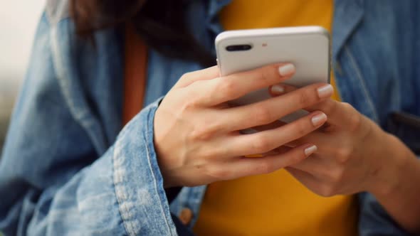 Closeup hand beautiful young Asian girl using smartphone texting messenger at outdoors.