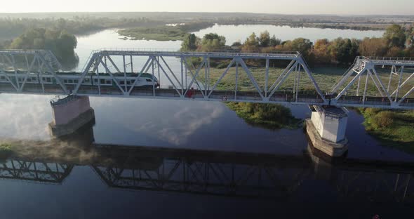 Train Passing Over a Vintage Arch Bridge Over the River on a Sunny Foggy Morning