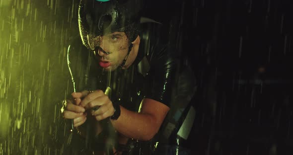 Triathlon Athlete Riding a Professional Racing Bicycle on an Intense Workout in Dark with Rain