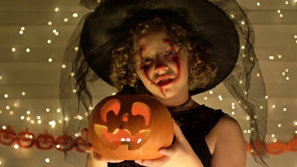 Portrait of a Teenage Girl Dressed As a Witch with Scary Makeup on Her Face, The Girl Holds a Jack