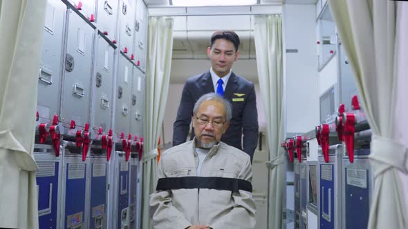 Asian Cabin crew or male flight attendant give service to senior older guy passenger on airplane. alt