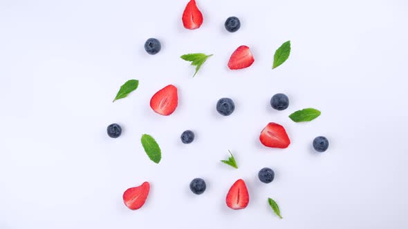 A Rotating Background of Blueberries Strawberries and Mint Leaves on a White Background the Concept