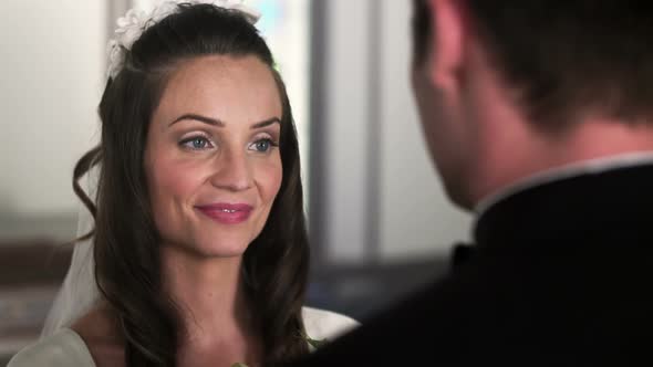 Bride looking up at the groom as they listen to the preacher. alt