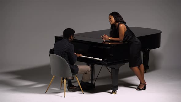 Stylish African American Romantically Sings and Plays a Melody on the Grand Piano for His Beloved alt