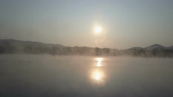 Cinematic Aerial Fly Through a Morning Fog Over a Mountain Lake. Foggy Sunrise In Mountains. alt