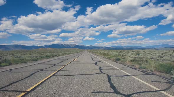 Small Asphalt Road Surrounded By Desert with Clouded Blue Sky. alt