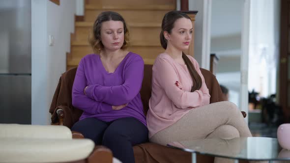 Argued Caucasian Mother and Daughter Sitting Back to Back on Couch at Home in Silence alt