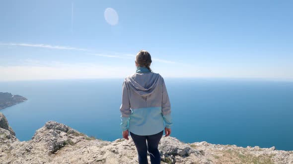 A Young Woman Traveler Climbed the Highest Cliff Overlooking the Endless Ocean alt