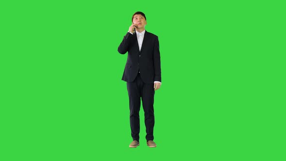 Asian Man in Office Suit Talking on Mobile Phone on a Green Screen Chroma Key alt