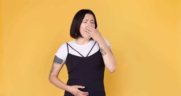Young stylish woman with tattoo yawns. Bored hipster yawning and covering mouth alt