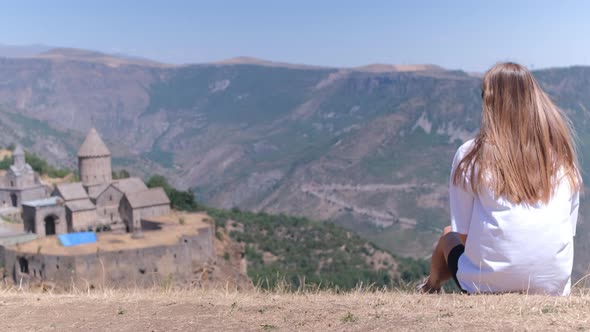 A girl is sitting against the background of mountains in Armenia