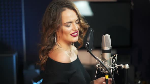 Young female singer recording album in the professional studio. alt