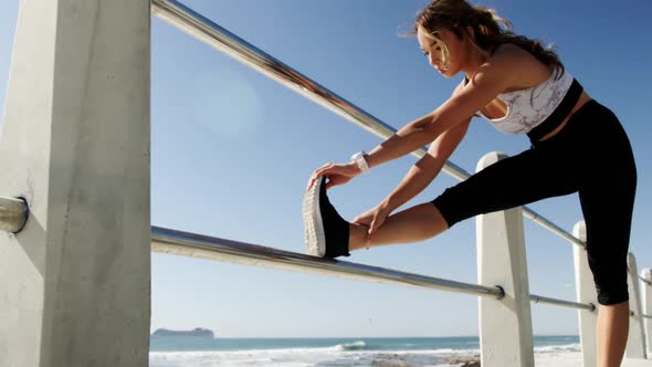 Beautiful Caucasian woman exercising on railing at beach 4k