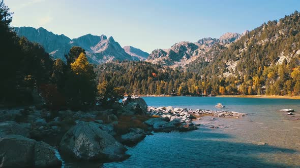 Flight along the water of a beautiful valley with a lake and mountains of the Pyrenees