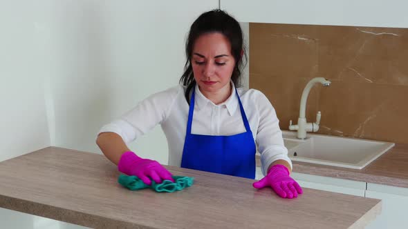 The Brunette Girl Is Engaged in Cleaning. He Wipes a Table Made of Light Wood