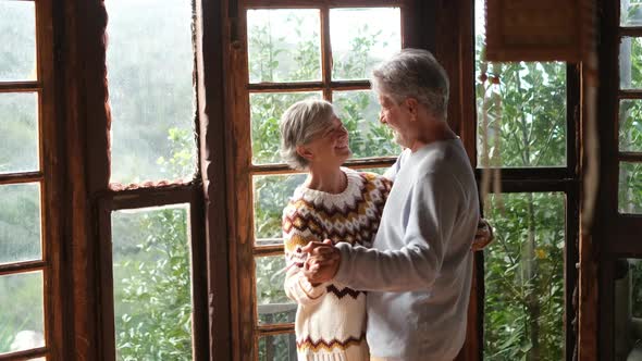 Happy senior couple smile and dance at home enjoying love and relationship together alt