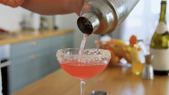 Woman with Shaker Pouring Cocktail Drink to Glass alt