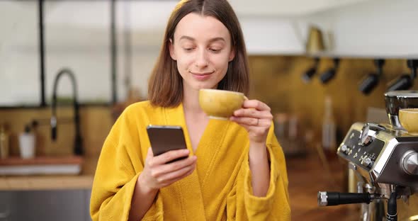 Woman with Coffee and Phone on the Kitchen in the Morning alt