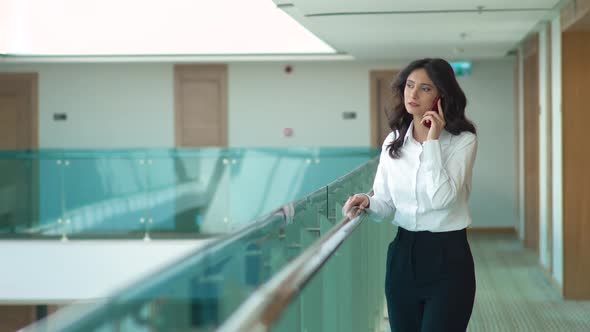 Businesswoman talking on the phone in the hallway. alt