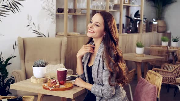 Portrait of an Attractive Young Woman Who is Sitting in a Cafe