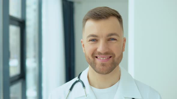 Successful Physician in White Lab Coat Looks at the Camera and Smiles in Hospital Office alt