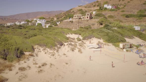 Aerial view of a group of people playing volleyball on a public beach in Greece. alt