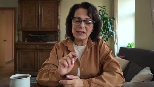 Woman Talking and Gesturing During Online Conference at Table in Home Office alt