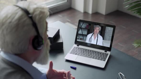 An Elderly Man with a Beard Communicates Via Computer with a Doctor Via Video Link. Medical Care in alt