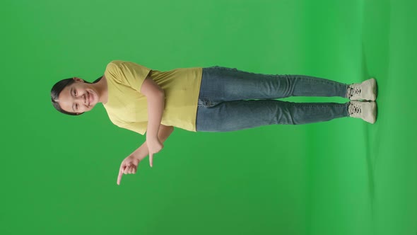 Full Body Of  Asian Kid Girl Smile And Pointing To The Side While Standing In The Green Screen alt